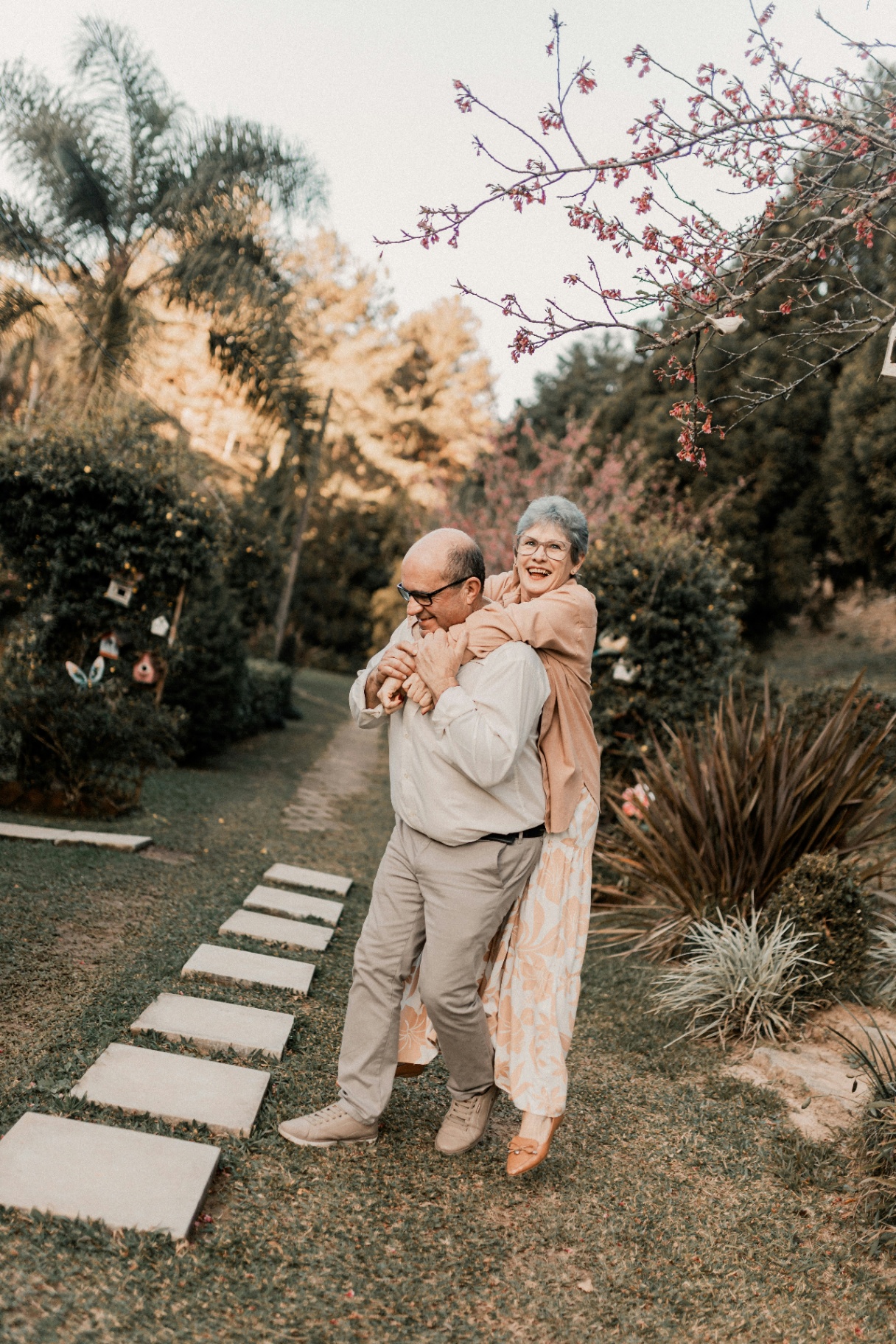 Older couple piggyback in a garden, joyful