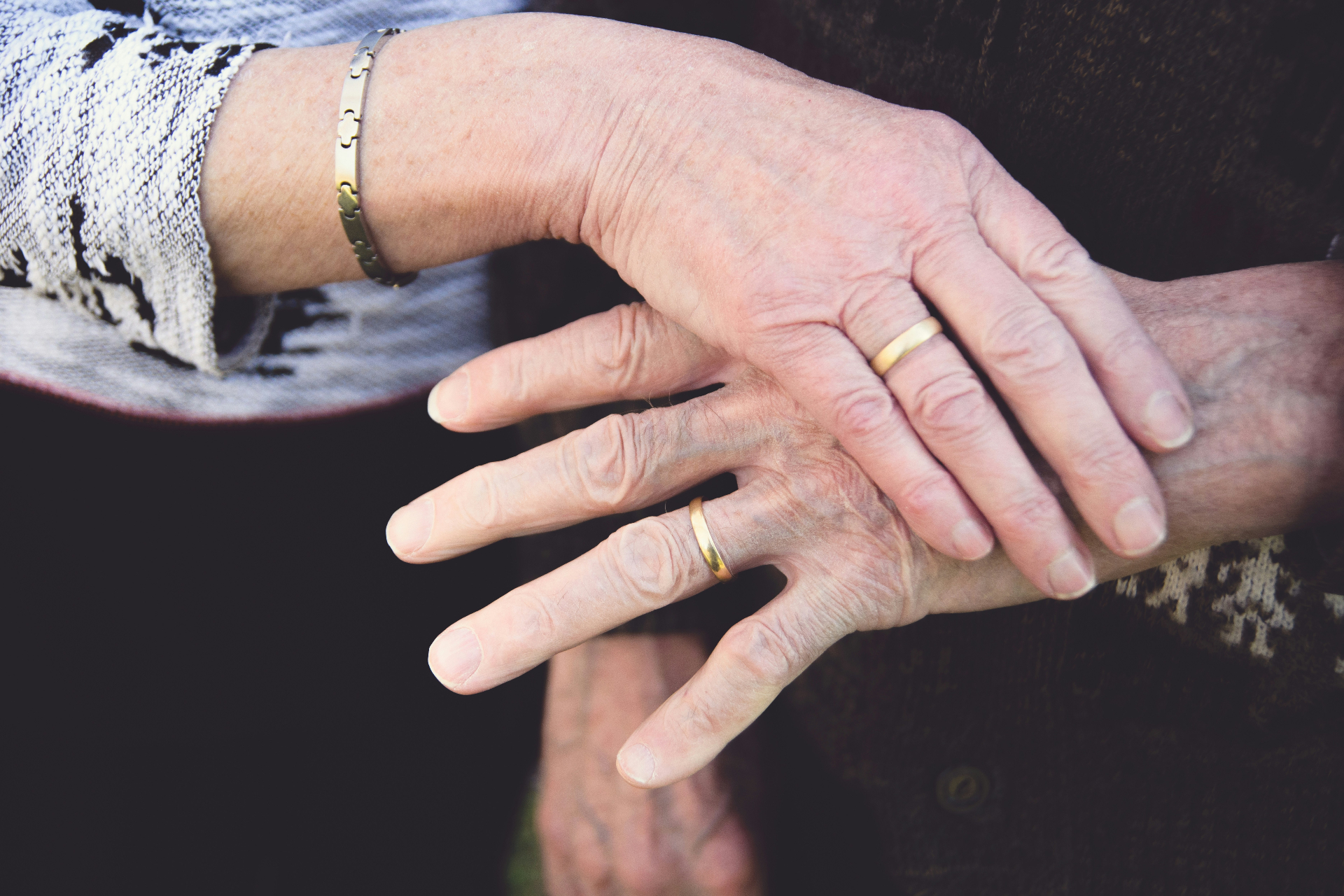Elderly hands clasped, wedding rings