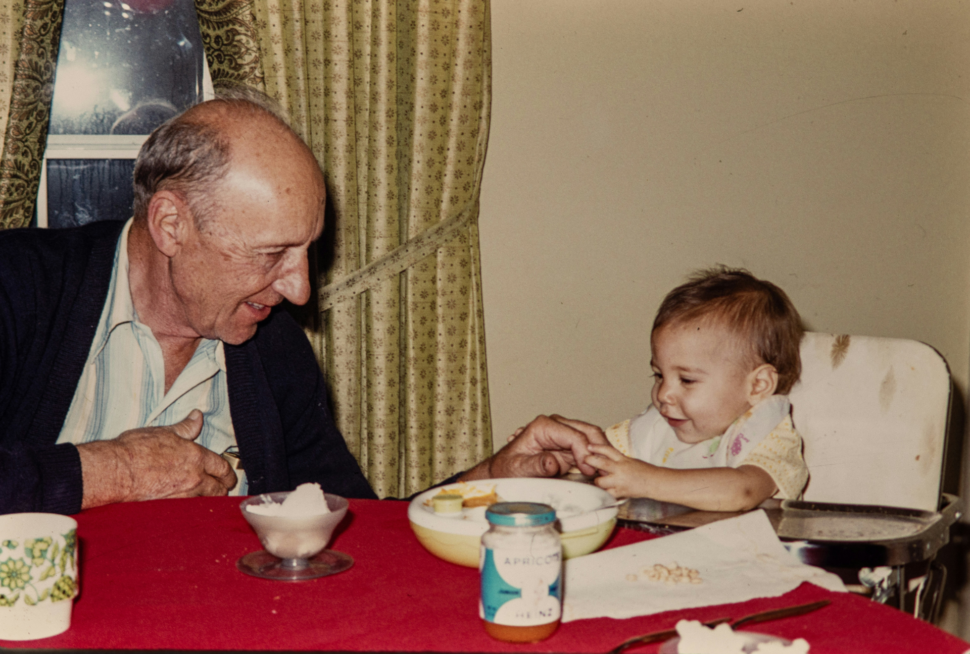 Grandfather feeding grandchild at the table, vintage color photograph